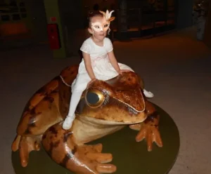 Anthoula is trying out how to sit on a Giant Frog
